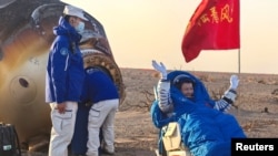 فضانوردِ شنژو-۲۰ در کنار کپسول بازگشت فضاپیمای شنژو-۲۱ در محل فرود دونگ‌فِنگ در منطقه مغولستان داخلی چین