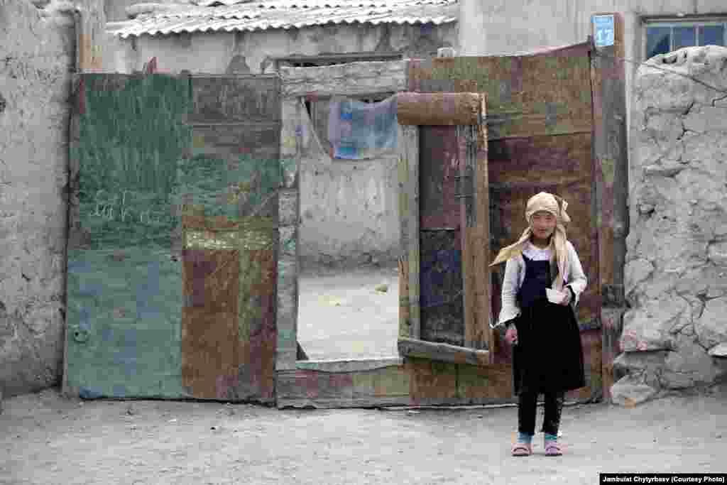 Сүрөттө: Ыраң-Көл айылынын кичинекей тургуну үйүнүн алдында турат. Ыраң-Көлдүн эли жалаң мал менен жан багат. Алар мал жайган жайлоолордун 70 пайызын Кытайга берүүнү караган талаштуу мыйзамды тажик парламенти быйыл 2013-жылы жактырды.