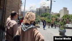 Тегерандын тургундары талкаланган имараттарды карап турат.