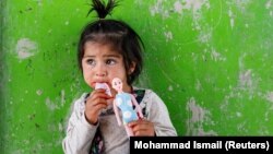 An internally displaced Afghan girl plays outside her shelter in Kabul in May.