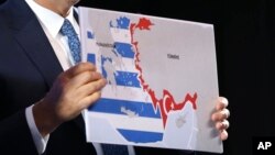 مولود چاووش‌اوغلو در کنفرانسی خبری در براتیسلاوا در اکتبر ۲۰۲۰، نقشه‌ای از حریم دریایی یونان و ترکیه را در دست دارد.