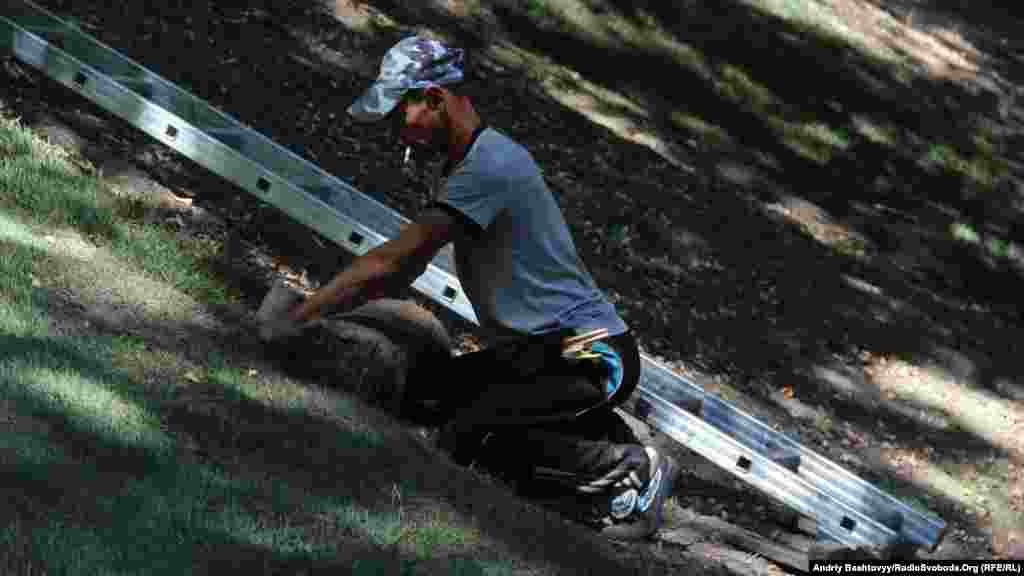 Працівники комунальних служб замінюють газон на Володимирській гірці.