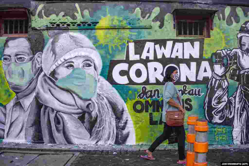 Жителька Індонезії проходить повз настінний розпис, який закликає людей боротися з коронавірусом. Сурабая, Східна Ява