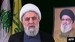 تصویر نعیم قاسم هنگام سخنرانی روز چهارشنبه در کنار عکسی از حسن نصرالله، دبیرکل کشته‌شده حزب‌الله لبنان