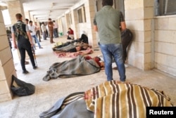 Люди осматривают тела убитых боевиками группировки ИГ в провинции Хасака в Ираке. Рас аль-Айн, 29 мая 2014 года.