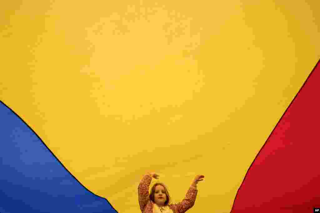 یک کودک در جریان تظاهرات طرفدار اتحادیه اروپا در بخارست در روز ۹ مه، قبل از برگزاری دور دوم انتخابات جنجالی انتخابات ریاست‌جمهوری، زیر پرچم بزرگ رومانی بازی می‌کند