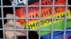 A gay rights activist holds a poster reading "Love is stronger than homophobia!" while sitting inside a police van after his detention at a rally in central Moscow in 2013.