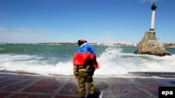 Ukraine -- A man drapes the Russian flag on his shoulders as he stands on the coast of the bay of Sevastopol, Crimea, March 17, 2014