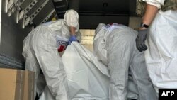 Эл аралык Кызыл чырым комитетинин өкүлдөрү аскер кызматкерлеринин сөөгү салынган каптарды текшерип жатат. (архивдик сүрөт.)