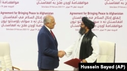 U.S. envoy Zalmay Khalilzad (left) and Mullah Abdul Ghani Baradar, the Taliban group's top political leader, shake hands after signing a peace agreement in Doha on February 29.