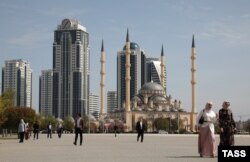 Люди на площі у Грозному. Височіють мінарети мечеті «Серце Чечні» та будівлі комплексу «Грозний Сіті». Під час двох російсько-чеченських воєн столиця Чечні була повністю зруйнована, а потім після приведення до влади прокремлівського Кадирова, Грозний відбудували за гроші Росії.