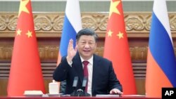 Chinese President Xi Jinping waves during a meeting with Russian President Vladimir Putin via video link in Beijing on December 30, 2022.