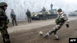 Ukrainian servicemen play football on a road at Svitlodarsk, approaching Debaltseve on February 15, hours after a cease-fire came into effect. The truce seems to have been cautiously observed by both sides, despite accusations by Kyiv and Washington that Russia had fueled a final push by rebels to gain territory before the start of the cease-fire.