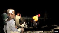 A boy covered in debris and with a bandage on his head awaits medical attention in Port-au-Prince late on January 13.
