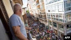 Мъж наблюдава от балкона си протеста срещу прекомерния туризъм в Палма де Майорка, Испания, 15 юни 2025 г.
