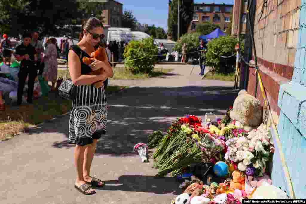 Жінка емоційно притискає до себе плюшевого ведмедика, якого вона принесла загиблим від російської атаки діткам, їх четверо. Київ, 29 серпня 2025 року