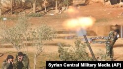 تصویر منتشر شده توسط تلویزیون مرکزی ارتش سوریه، نیروهای دولتی این کشور را در حال شلیک خمپاره به سوی مواضع معارضان بشار اسد