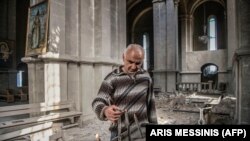 A man lights a candle inside the war-damaged Armenian Ghazanchetsots (Holy Savior) Cathedral in Shushi on October 8, 2020, a month before Nagorno-Karabakh’s historic city was captured by advancing Azerbaijani forces. 