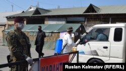 Атайын кызматкерлер Сузак районунун аймагына кирип бараткан жүк ташуучу автоунааны дезинфекциялап жатат.