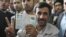 Iran -- Iranian President Mahmud Ahmadinejad flashes the victory sign with an ink-stained finger as he holds up his identity cards at a polling station in Tehran, 12Jun2009