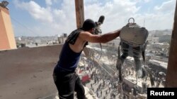 مردی در حالی که تجهیزات مورد استفادهٔ حسام المصری، فیلمبردار طرف قرارداد خبرگزاری رویترز، را در دست دارد، به مرگ او، دیگر روزنامه‌نگاران و مردم در حملات اسرائیل به بیمارستان ناصر، واکنش نشان می‌دهد