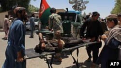 Afghan men carry a victim of a powerful car bomb in Lashkar Gah on June 22.