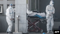 Медики у спеціальних костюмах транспортують інфікованого коронавірусом до лікарні, місто Ухань, 18 січня 2020 року