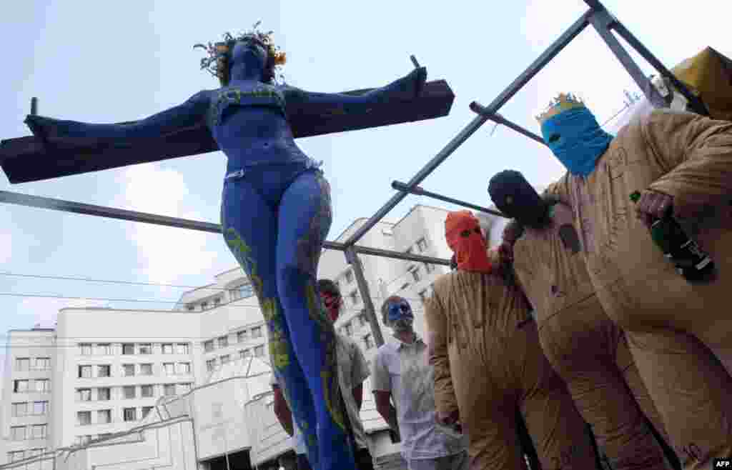 Україна &ndash; Дівчина, яка символізує українську Конституцію, &laquo;розп&rsquo;яту на хресті чинної влади&raquo;, під час акції &laquo;руху Гая Фокса&raquo; біля Конституційного суду в Києві, 27 червня 2013 року