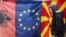 A man walks by Albanian EU, and Macedonian flags displayed in a bazaar in Skopje.