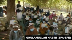 Afghans wait to receive cash from a counter in Nangarhar Province on November 8. Kabul will see cuts in donations at a time the World Bank estimates the Afghan economy will contract by at least 5.5 percent this year because of COVID-19 impacts. 