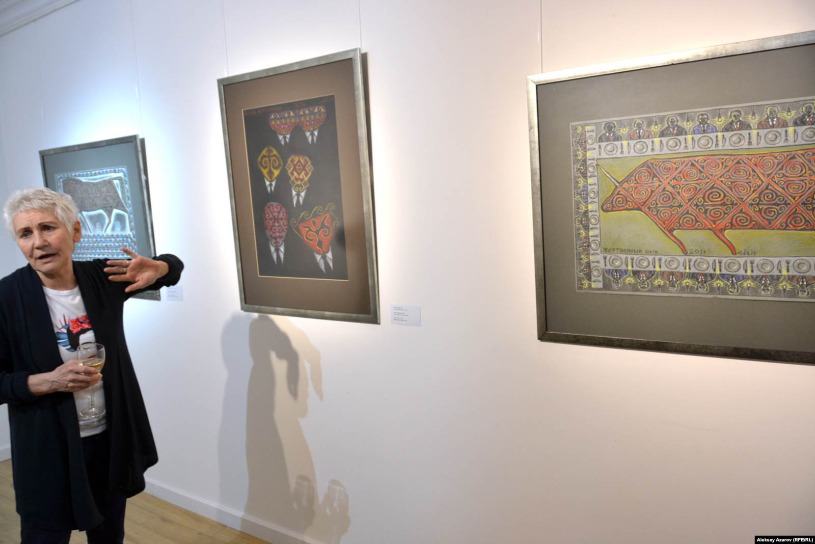 Көрме кураторы Валерия Ибраева "Ат және аттың күші" жұмысының жанында тұр. Ортада – "Ақ жағалылар", оң жақта – "Құрбанға шалынған бұқа" туындысы. Алматы, 4 сәуір 2019 жыл.  