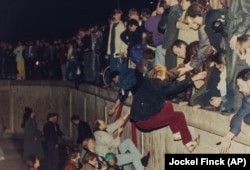 در این تصویر مربوط به ۱۰ نوامبر ۱۹۸۹، شهروندان غرب برلین به ساکنان بخش شرقی آن برای بالا رفتن از دیوار کمک می‌کنند