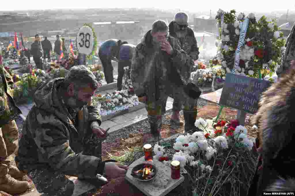 Men in military uniform at Yerablur cemetery on December 19 at the grave of a volunteer who died in the conflict