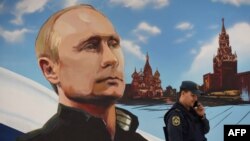 A man passes a wall bearing an image of Russian President Vladimir Putin and Moscow's Kremlin at a polling station during local elections organized by the Russian-installed authorities in Donetsk, Ukraine, on September 8.