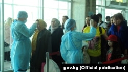 Медицина кызматкерлери чек арадан өтүп жаткан адамдардын дене табын өлчөп жатат. "Манас" аэропорту. Февраль, 2020-жыл. 12-мартта өкмөт коронавирус коркунучуна байланыштуу маданий, спорттук жана башка массалык иш-чараларды өткөрүүгө убактылуу чектөө киргизген.