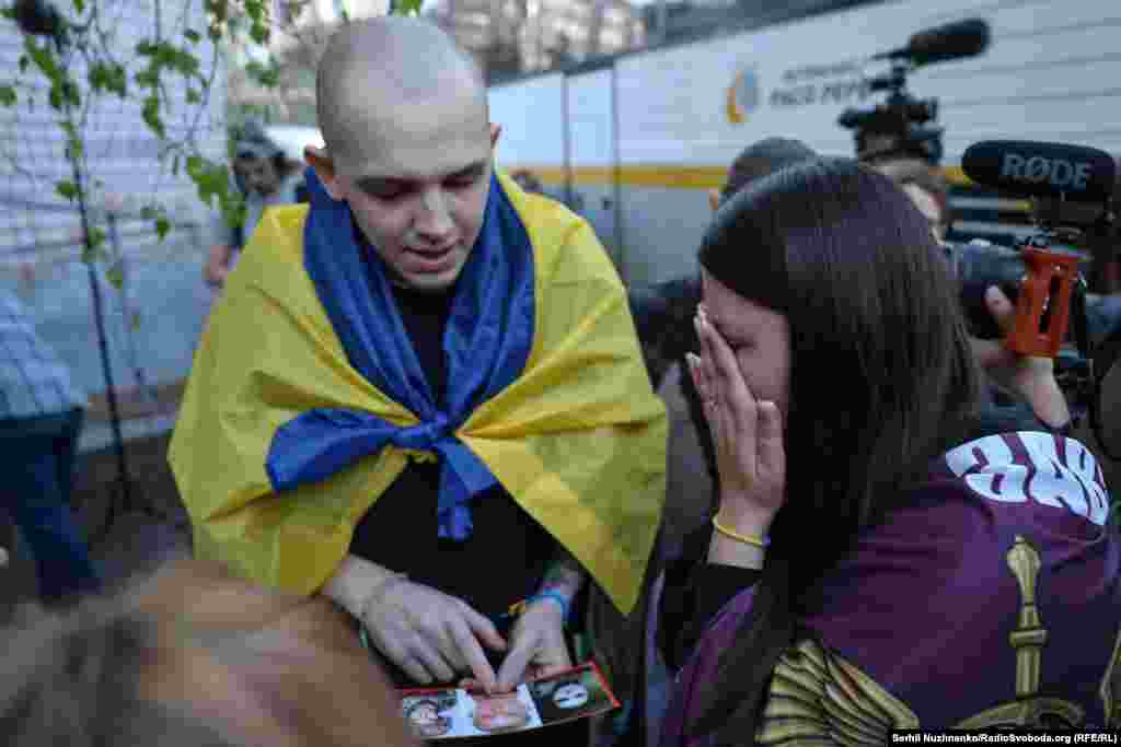 Дружина українського захисника, який досі перебуває в російському полоні показує фото свого чоловіка, щоб дізнатися інформацію про нього