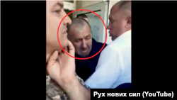 Сергій Торбін в оточенні людей у камуфляжі не пропускає в приміщення районної адміністрації міста Олешки членів іншого місцевого об’єднання ветеранів «Кордон»