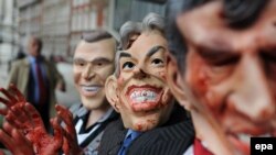 Лондондо коомдук угуу башталганда эшикте пикетчилер Жорж Буш, Тони Блэр, Гордон Браундун канга боелгон маскаларын кийип турушту. 24-ноябрь, 2009-ж.