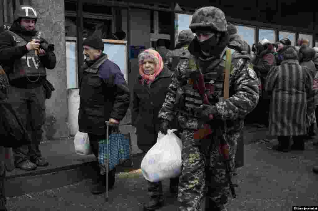 Uzbekistan/Russia- Debaltsevo township, Donetsk region, Ukrain. The territory is under ukranian control. The center of distribution of humanitarian aid in a former city hall. Ukrainian soldier helps an old woman to carry her bag with humanitarian aid.