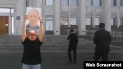 Риза Алимнур с портретом своего отца Алимнура Турганбая у здания акимата Алматы