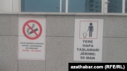 Плакат с предупреждениями о запрете курения (слева) на стене административного здания в Ашгабате.