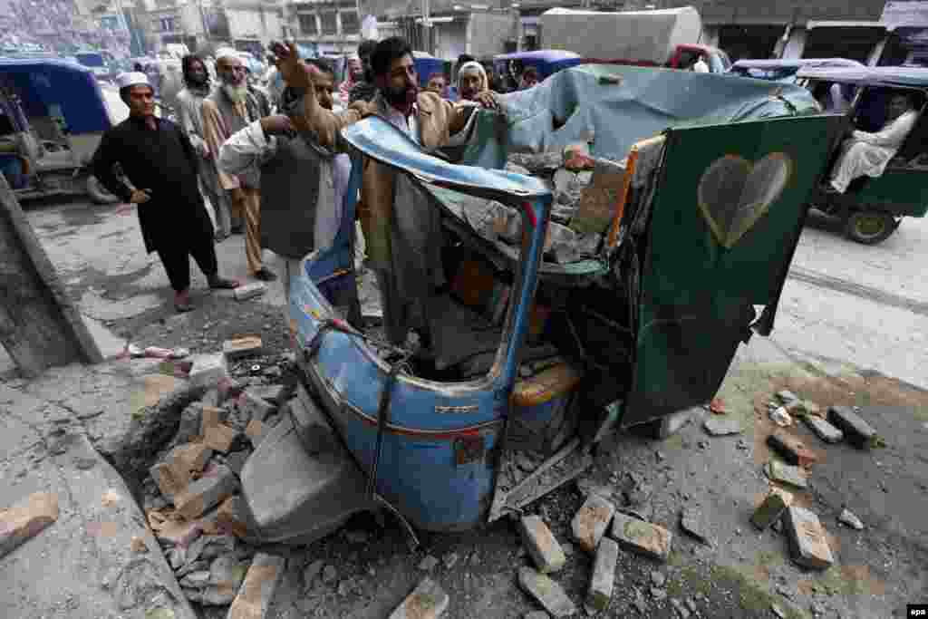 People remove debris from a rickshaw in Peshawar, Pakistan.