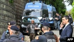 Мужчина с подносом с чашками и чайником проходит мимо итальянских полицейских у одного из входов в посольство Омана в Риме, 19 апреля 2025 года.