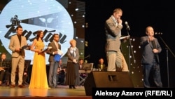 «Бастау» фестивалі президенті Сергей Азимов (оң жақта) сөйлеп тұр. Оның сырт жағында (үш жүргізушінің оң жақ шетіндегі) Темірбек Жүргенов атындағы Қазақ ұлттық өнер академиясының ректоры Бибігүл Нүсіпжанова тұр. Алматы, 24 қазан 2016 жыл.