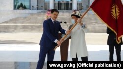 Министрлер кабинетинин башчысы Улукбек Марипов Кыргызстандын курама командасынын капитаны Атабек Азисбековго Кыргызстандын желегин тапшырган учур, 13-июль 2021-жыл.