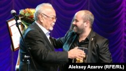 Қазақстандық танымал актер Асанәлі Әшімов  «Еуразия» кинофестивалінің гран-при жүлдесін Израиль режиссері Асаф Корманға тапсырып тұр. Алматы, 19 қыркүйек 2014 жыл. 