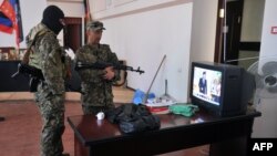 Вооруженные пророссийские активисты смотрят новости по ТВ в захваченном здании горсовета Краматорска