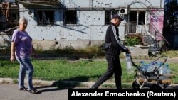 Люди йдуть повз пошкоджений обстрілами будинок в окупованому Кураховому Донецької області. Армія РФ, за даними DeepState, захопила місто у ніч проти 11 січня 2025 року