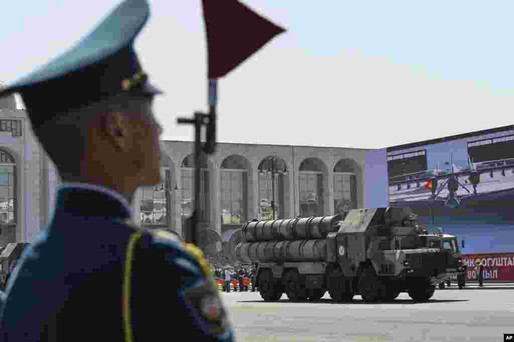 یک سرباز قرقیزستانی در حین رژهٔ نظامی در بیشکک برای بزرگداشت روز پیروزی در جنگ جهانی دوم ایستاده به تماشا نشسته است