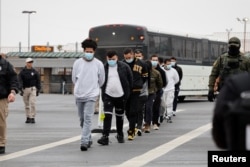 АҚШ-тан депортациялануы тиіс азаматтардың сақшылар қадағалауымен ұшаққа бара жатқан сәті. 27 қаңтар 2025 жыл.